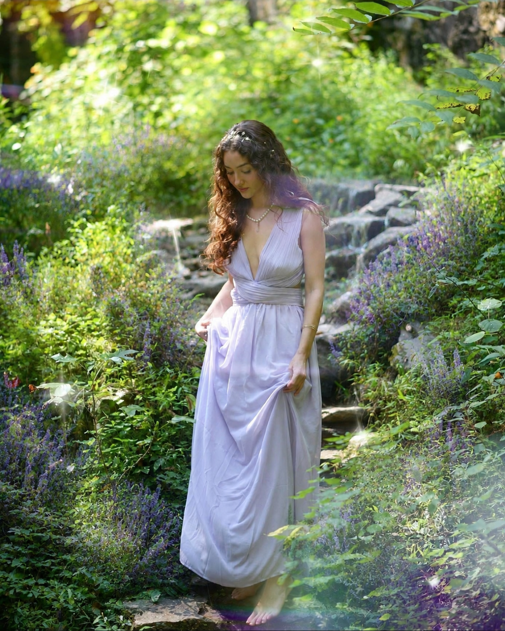 Young woman in a lavender dress walking through a lush botanical garden